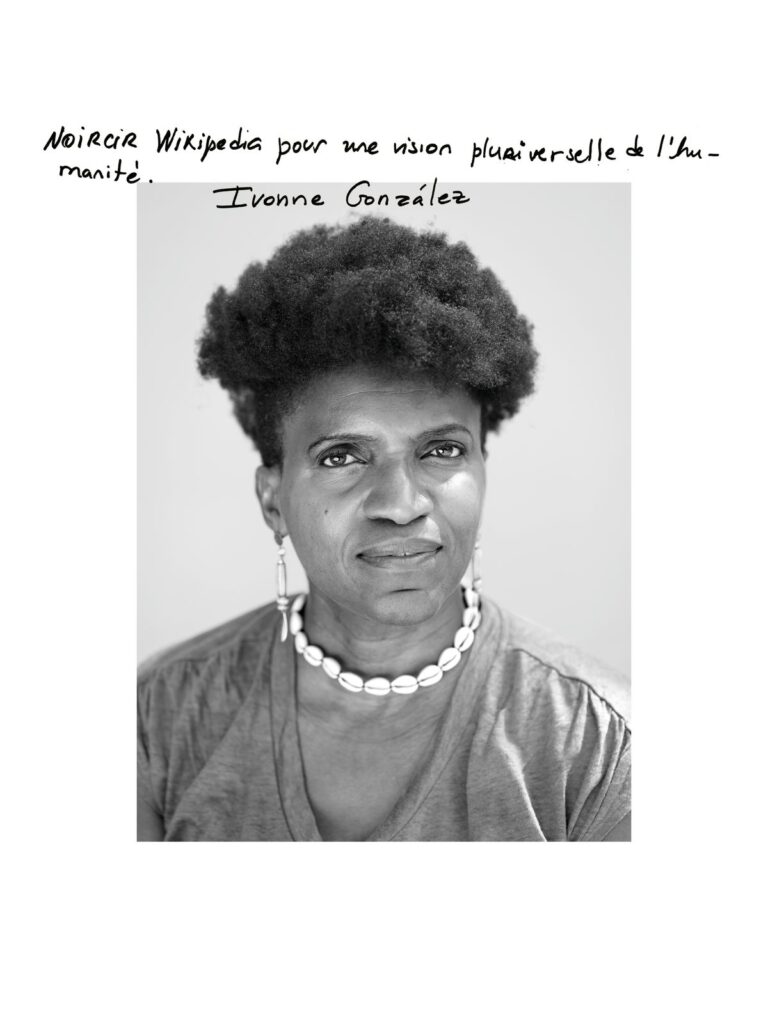 صورة شخصية لـ Ivonne González بعدسة جورجيا. الجملة المكتوبة باليد: «Noircir Wikipédia pour une vision pluriverselle de l’humanité.»